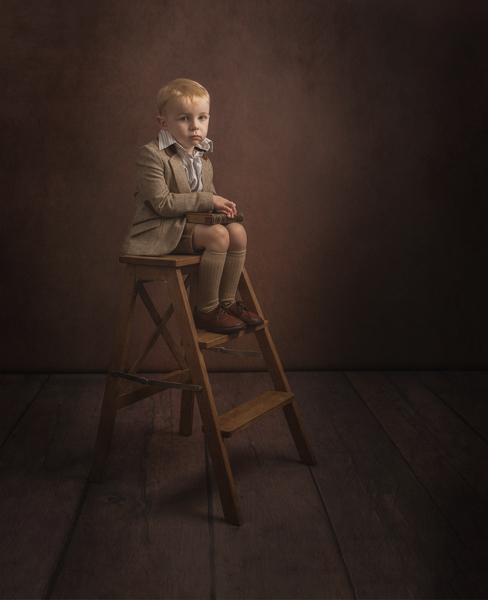 young boy sitting on a stepladder