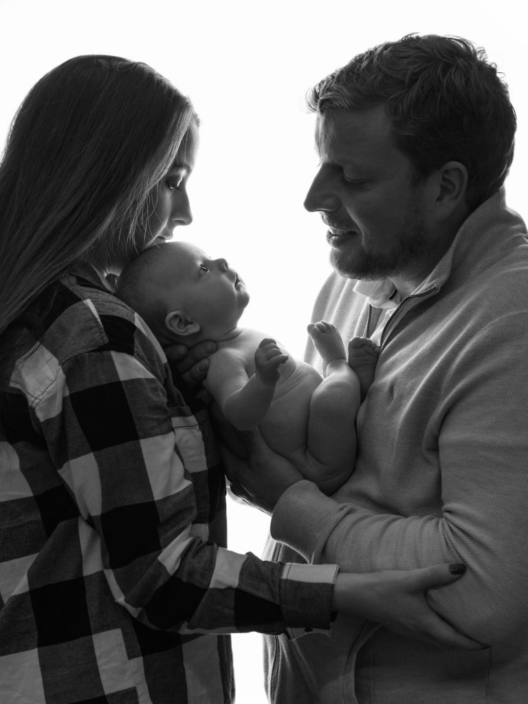 newborn baby with mum and dad together black and white photo