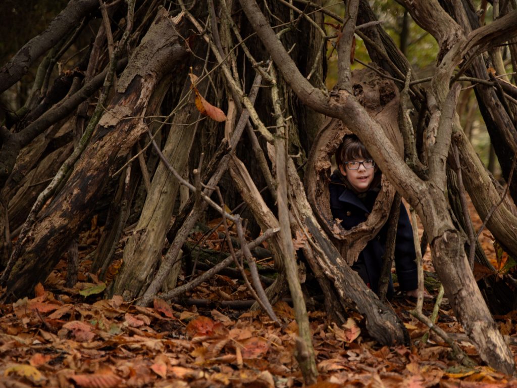 child playing hide and seek in the woods