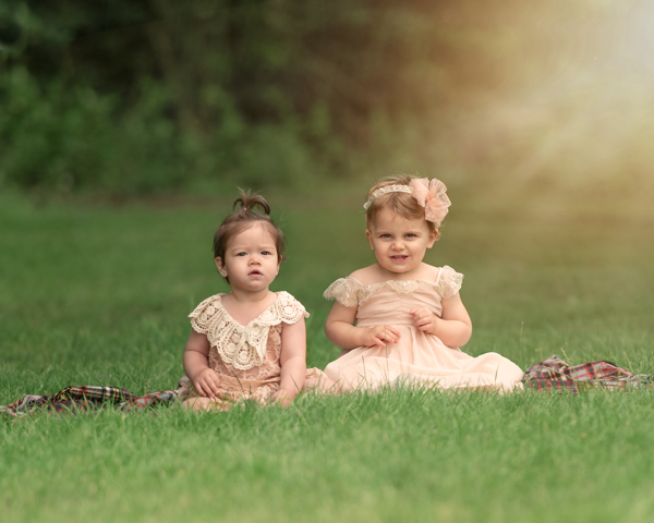 two baby girls in dresses on the grass