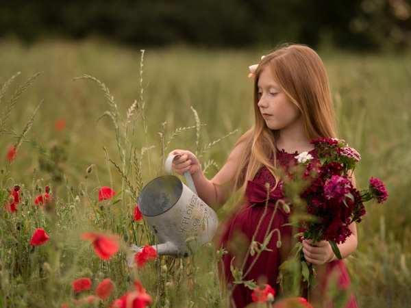 red haired girl in a field of poppies