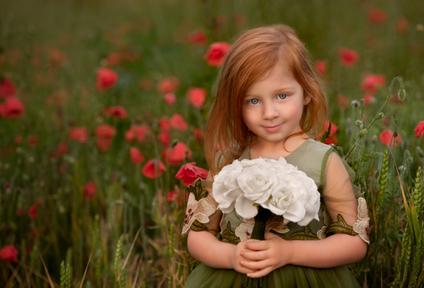 girl in a poppy field with a bunch of flowers