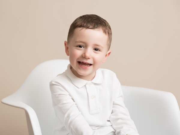little boy smiling in white chair