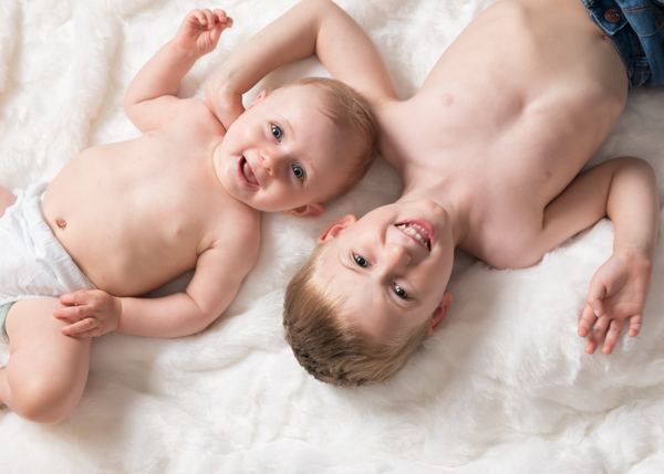 two young children smiling at the camera while lying down