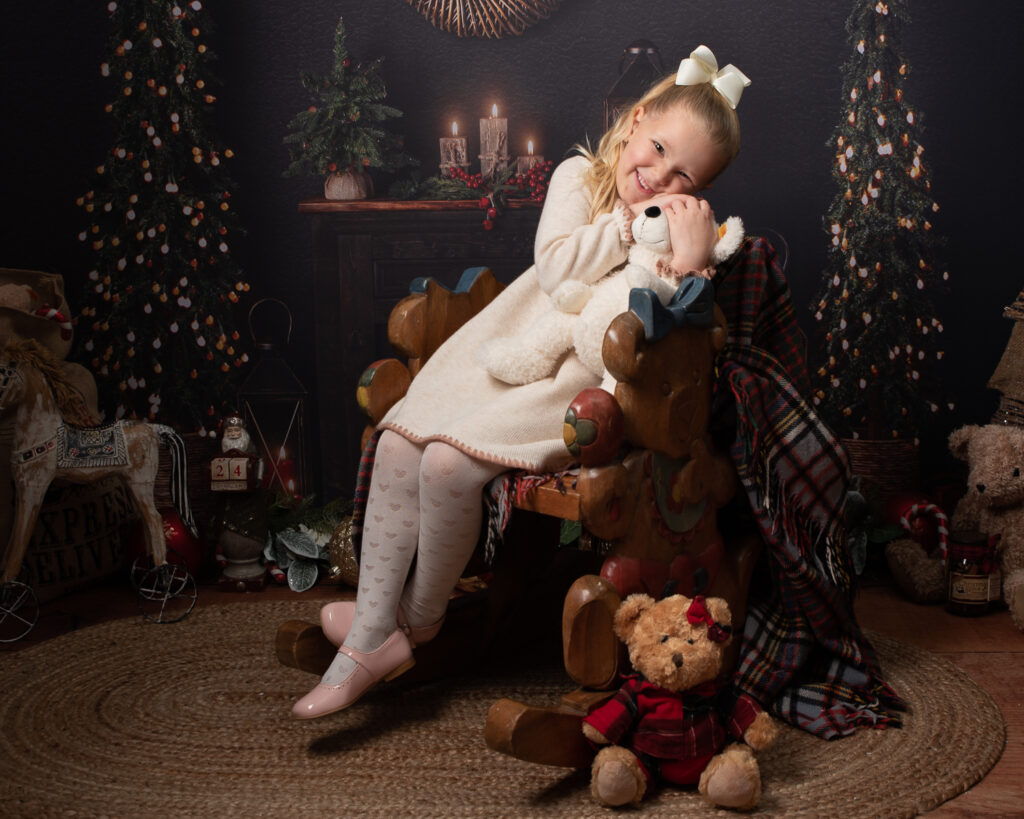 Cute girl cuddling teddy in Christmas photoshoot