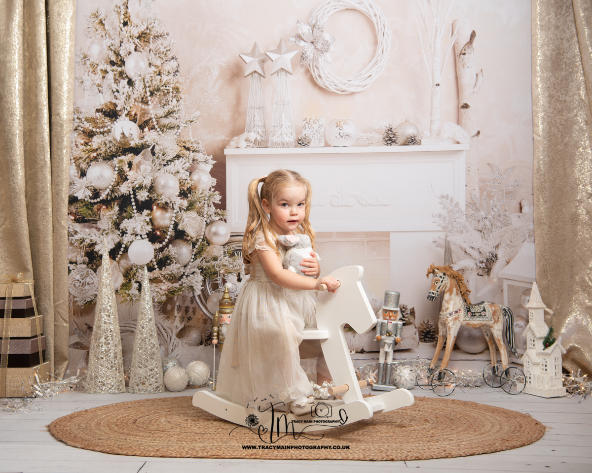 Cream and Gold Christmas scene girl in front of fireplace on rocking horse photoshoot