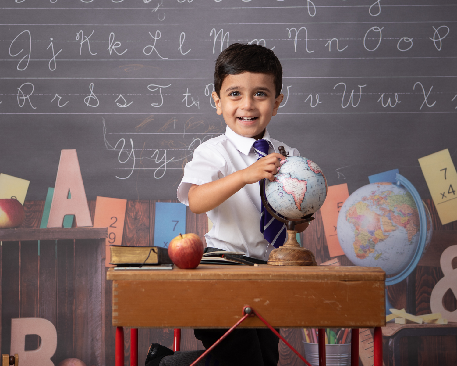 Boy with school uniform at desk with globe