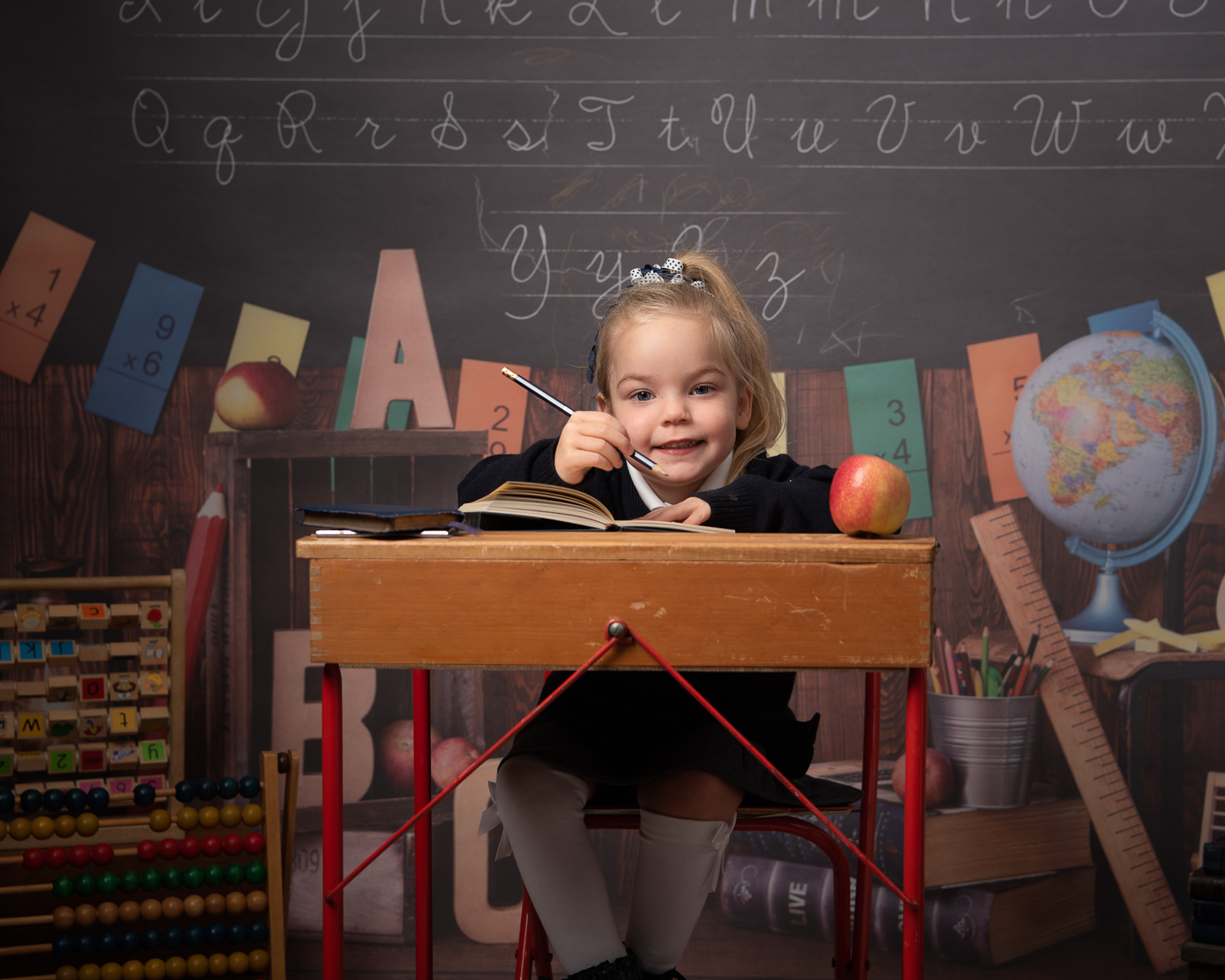 Back to school photo. Little girl at school desk with pencil and book in school uniform