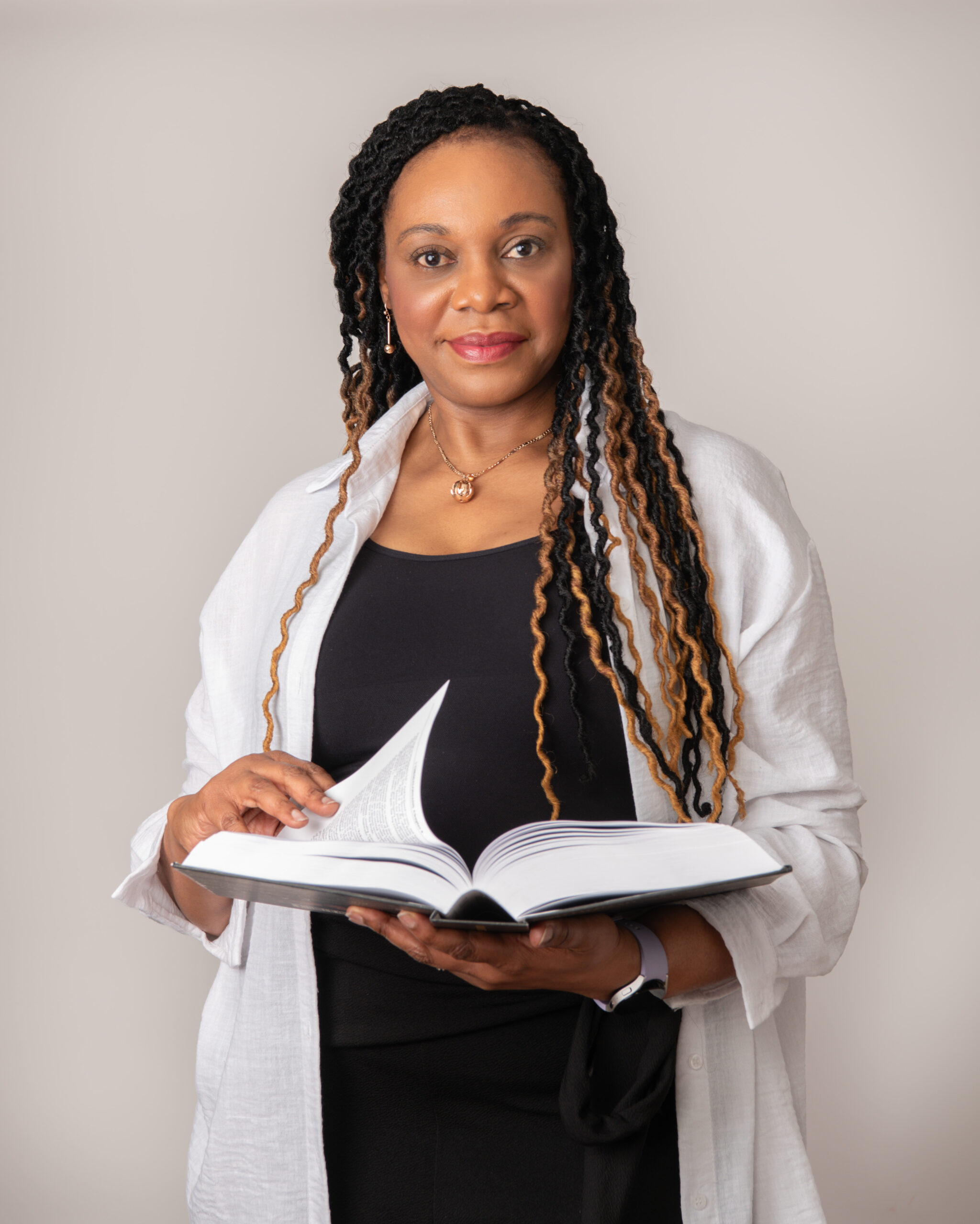 Persoanl brand photoshoot lady reading booking standing in white shirt with black top under it