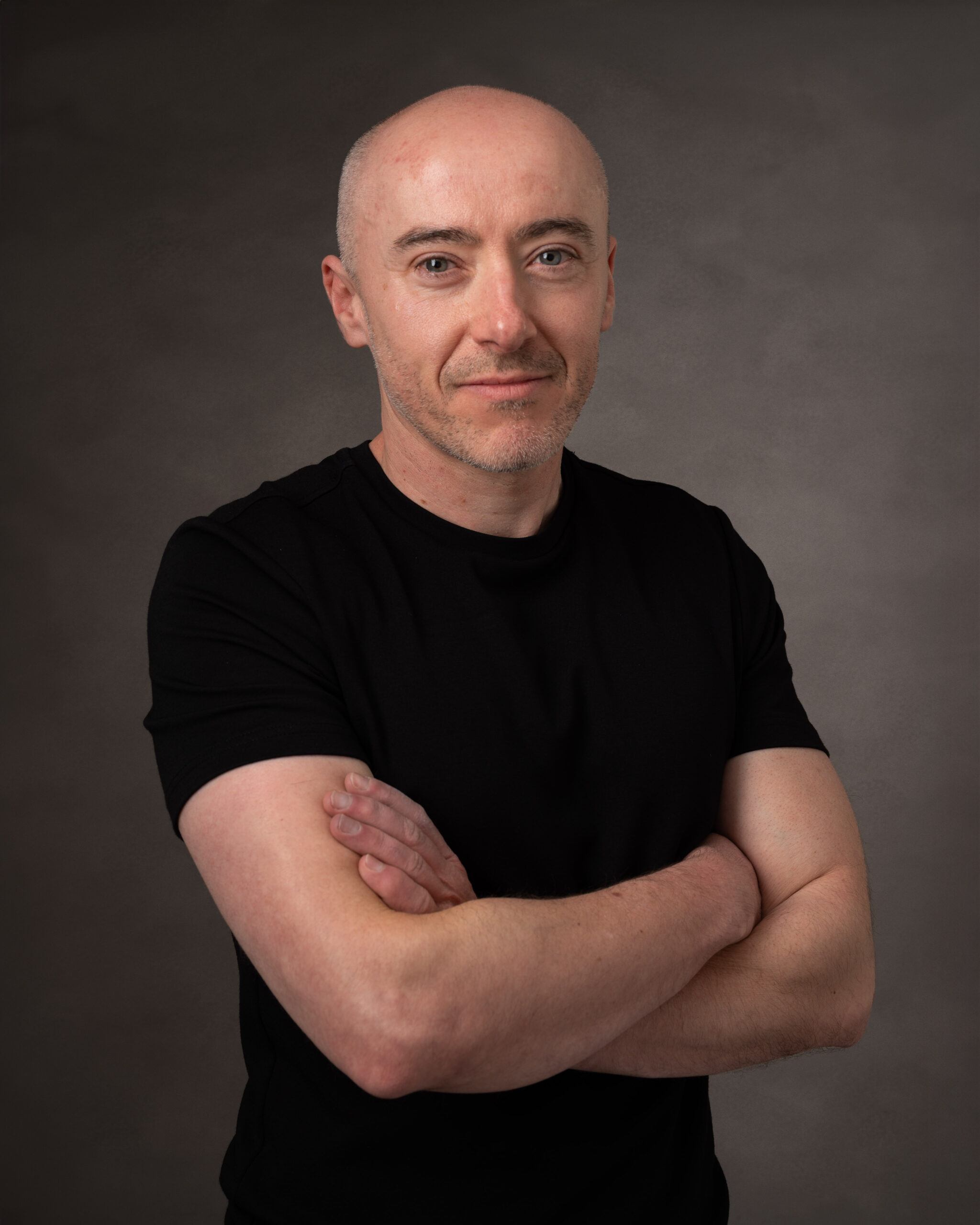 Dating profile image professional headshot of man with crossed arms in black t-shirt