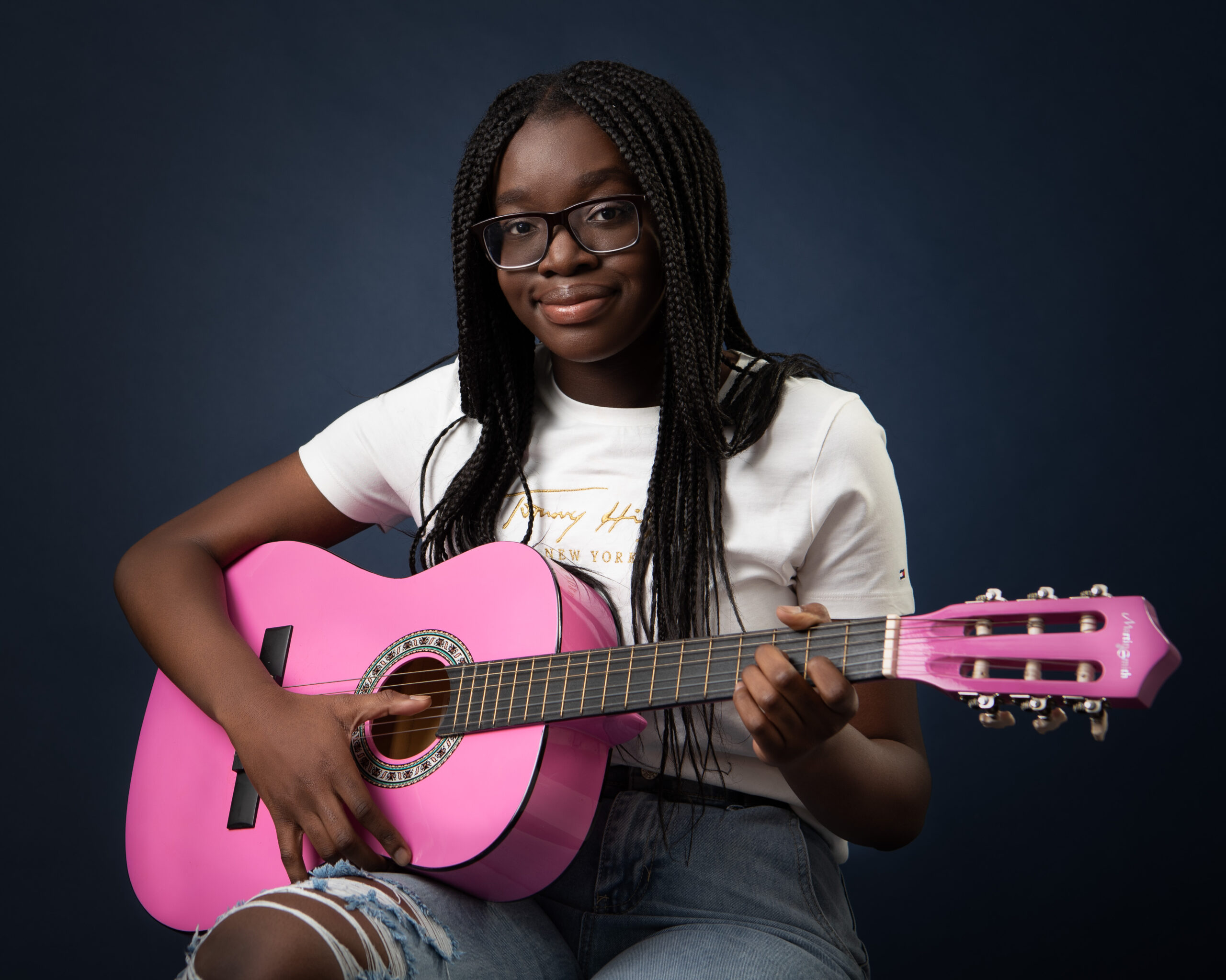 _TJM2235-Edit Teenage girl with dreadlocks in ripped jeans white t shirt playing pink guitar