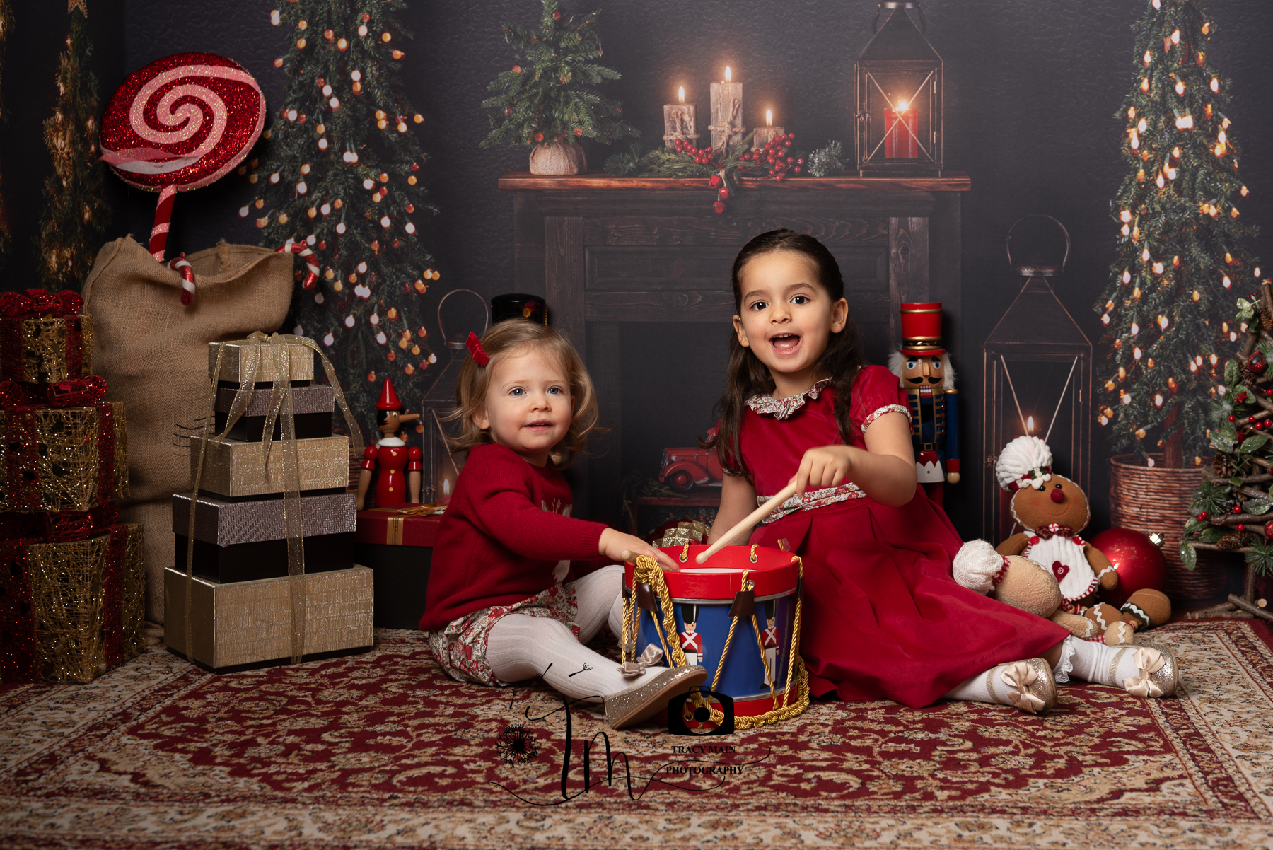 Two girls playing a drum in front of the fire at Christmas time