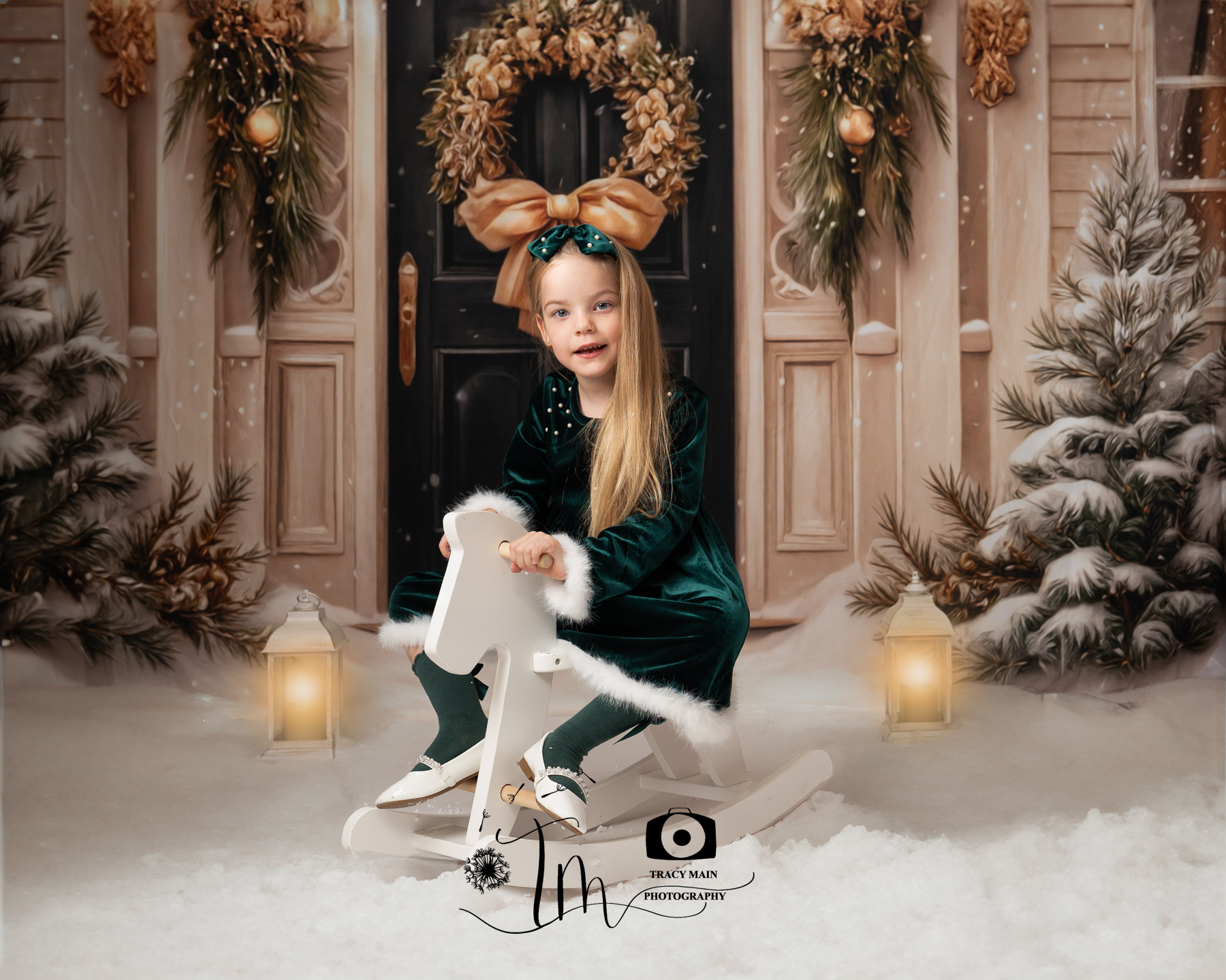 TMP_5412-Edit Christmas picture of a girl in a green dress on a white rocking horse in the snow in front of a festive house